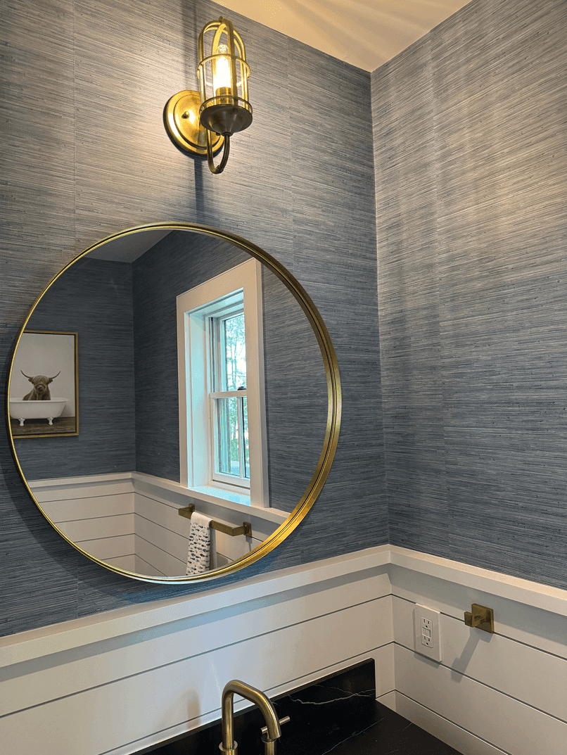 Blue grasscloth wallpaper with round brass mirror